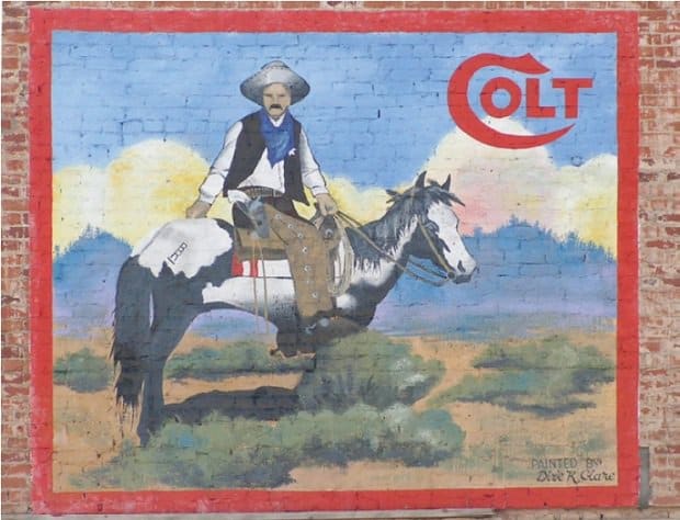 Painted sign on a wall for Colt showing a cowboy on a horse