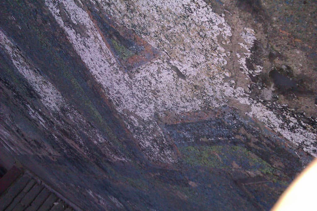 Fading sign on wall with hints of colour around the white letters