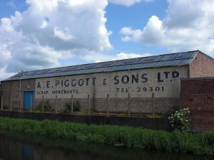 A.E. Piggott & Sons by Djinn76 Hand-painted sign on the wall of a warehouse beside a canal