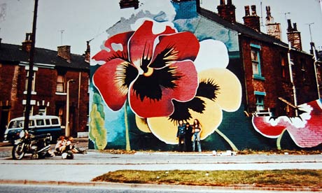 Oversized pansies painted on a wall with people standing in front of it