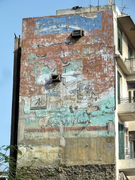 Fading painted sign on a wall advertising Laughing Cow