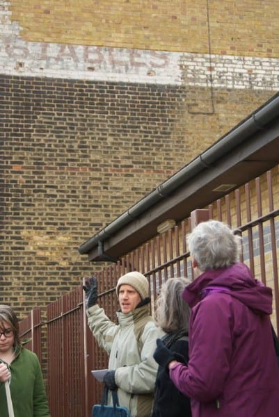 Tour group looking at a faded advertisement painted on a wall
