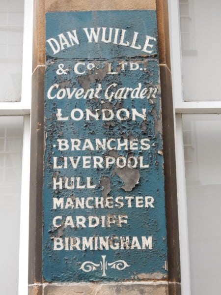 Painted panel stating branches of Dan Wuille & Co