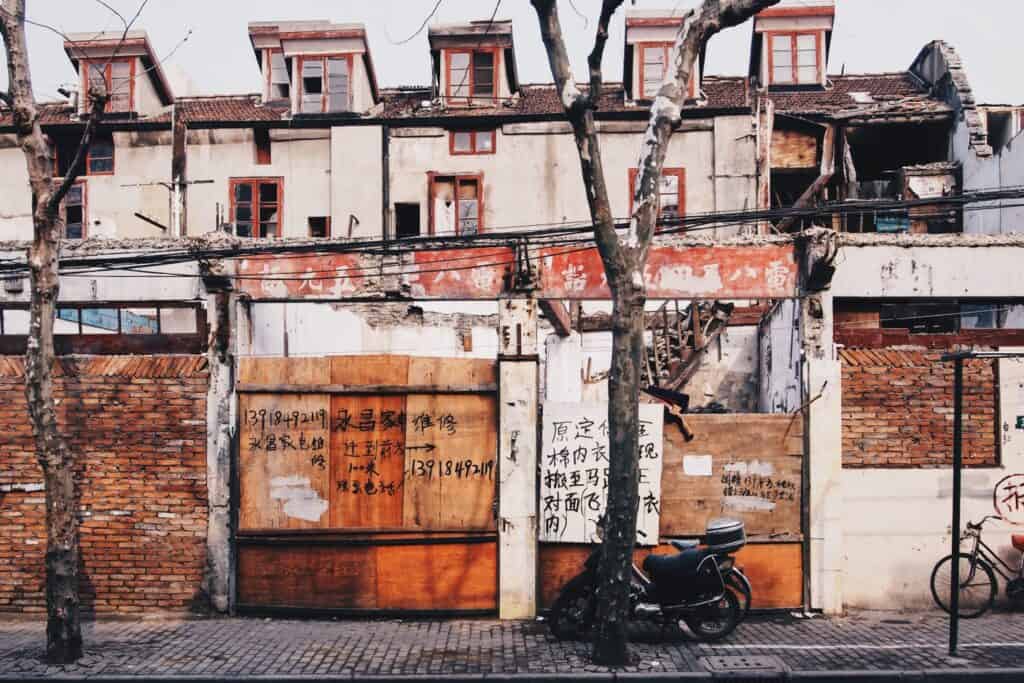 Fading painted lettering with Chinese characters across boarded up windows.