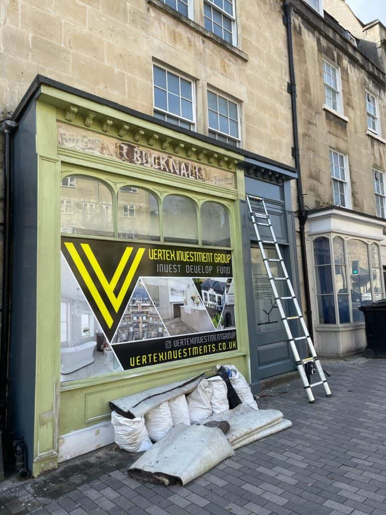 Shopfront with three layers of painted signs, close to being painted over.